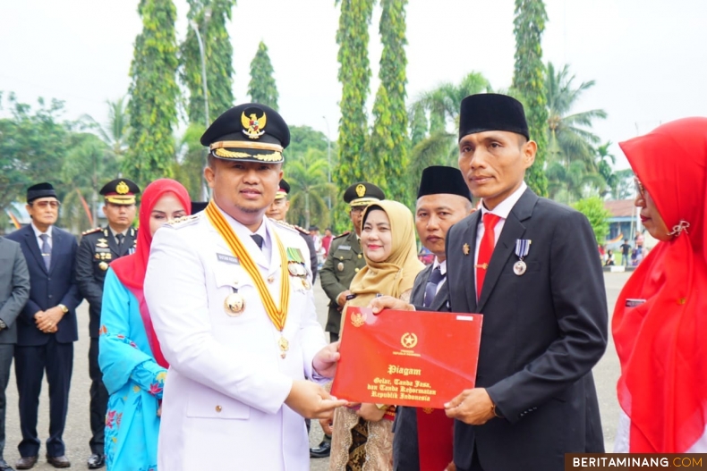 Sutan Riska menyerahkan piagam penghargaan pengabdian PNS di lingkungan Pemkab Dharmasraya. Foto: Kominfo Dharmasraya