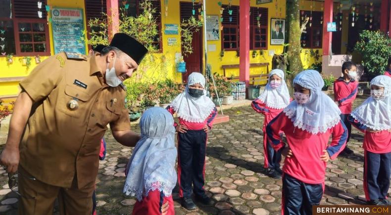 Bupati Pasaman H. Benny Utama menyapa siswa yang mulai masuk sekolah. Foto: Budhi Hermawan