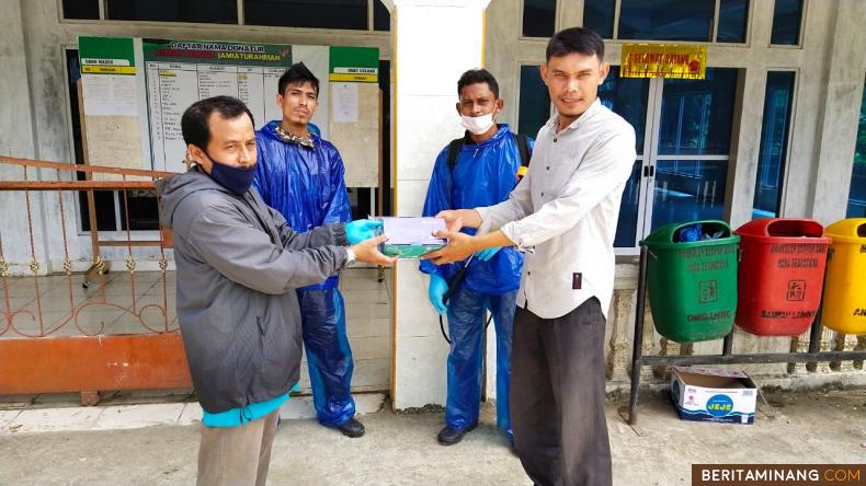 Wali Nagari Bomas Yuli Herman menyerahkan masker pada pengurus masjid usai melakukan penyemprotan disinfektan, Sabtu (24/5/2020). Foto Afrizal. A