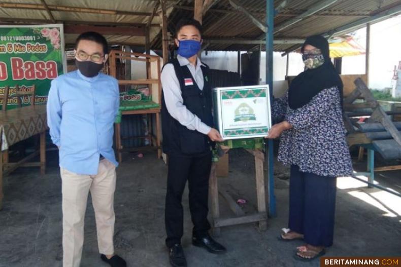 Salah seorang warga serahkan bantuan pada tim relawan untuk keluarga positif Covid-19 di Ampang Kuranji Padang. Foto Humas Padang