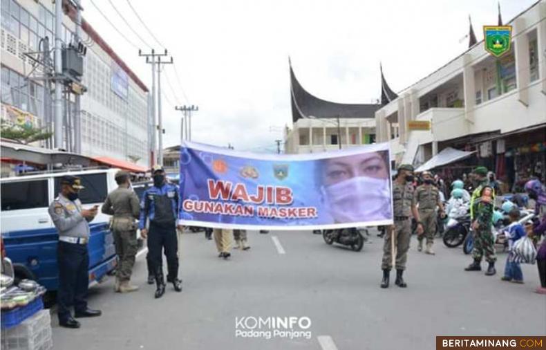 Tim Gabungan membawa spanduk dalam razia masker di Pasar Pusat Padang Panjang.