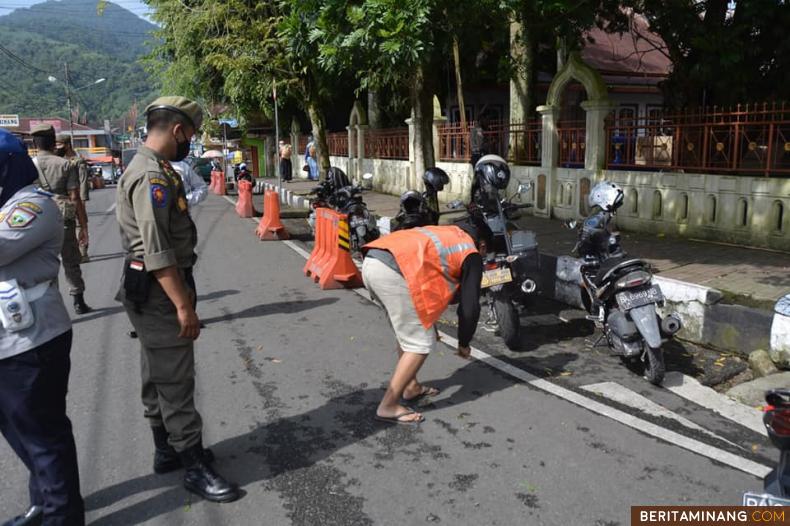 Seorang pelanggar aturan adaptasi kebiasaan baru (AKB) yang sedang menjalani sanksi sosial membersihkan fasilitas umum (fasum) dengan memakai rompi pelanggar prokes, Senin (22/3).