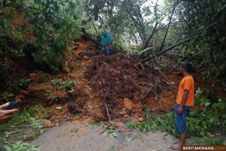 Seorang wanita berusaha menembus tanah longsor di Lolo kecamatan Pantai Cermin Kabupaten Solok, Senin (1/1) sekitar pukul 05.00 WIB. Longsor mengakibatkan jalur Solok Muara Labuh putus. Foto: Suhanews