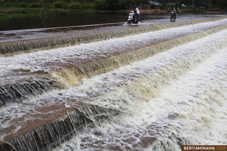 Warga melintas di Danau Irigasi Taram untuk mengantar anaknya pergi sekolah di Kapalo Banda, Taram, Limapuluh Kota, Sumbar, Rabu (16/3/2022). Danau Irigasi Taram selain berfungsi untuk pengairan sawah dan perkebunan merupakan destinasi wisata air yang ramai dikunjungi setiap akhir pekan. (Beritaminang/AP).