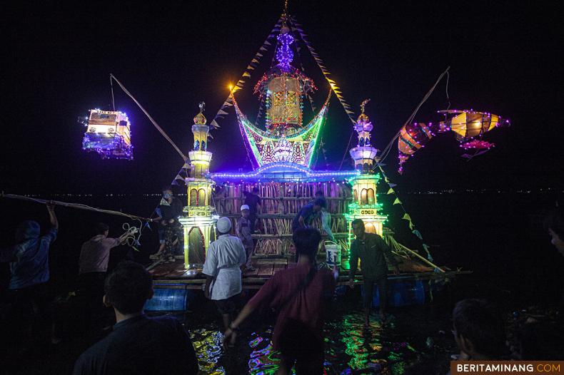 Warga memasang lampu dan menghias Rakik-Rakik (rakit) yang menyerupai rumah adat dan masjid di Danau Maninjau, Kabupaten Agam, Sumatera Barat, Indonesia, Senin (2/05/2022). Menyambut Hari Raya Idul Fitri, masyarakat di tepi Danau Maninjau menggelar tradisi membuat rakik-rakik hias untuk mengarungi Danau Maninjau dan tradisi ini menjadi daya tarik tersendiri bagi perantau yang pulang lebaran. (Beritaminang/Adi Prima).